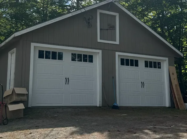 A large garage with two white garage doors is being built.