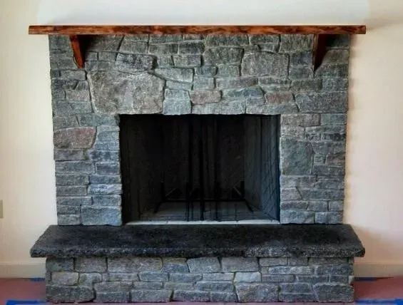 Dark ledge stone fireplace with rustic mantel
