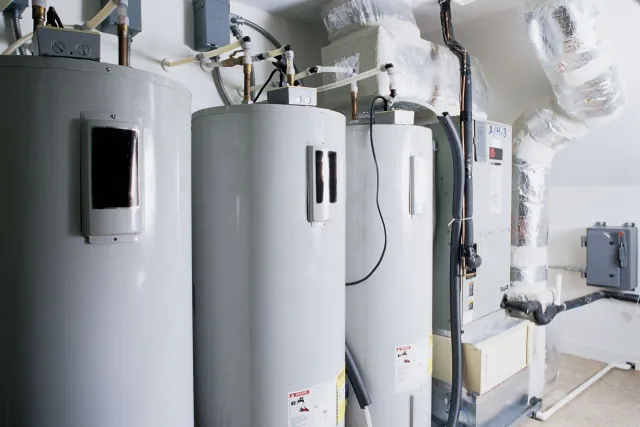Three water heaters in a utility room, with associated ductwork and controls.
