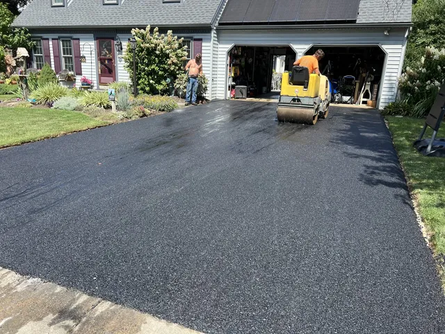 Roller compacting a new driveway by the garage