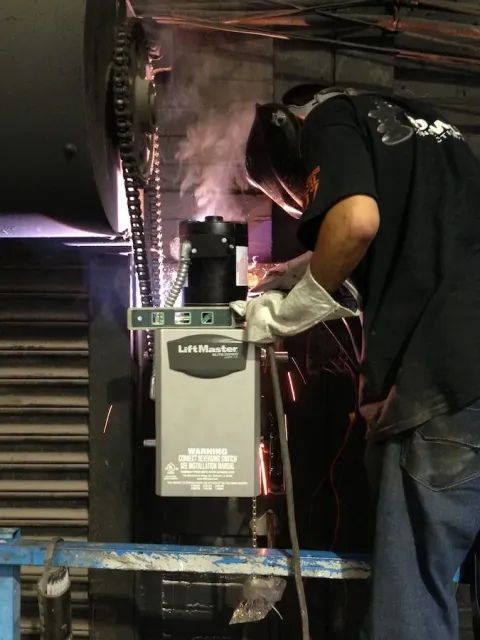 A man is working on a garage door with a drill.