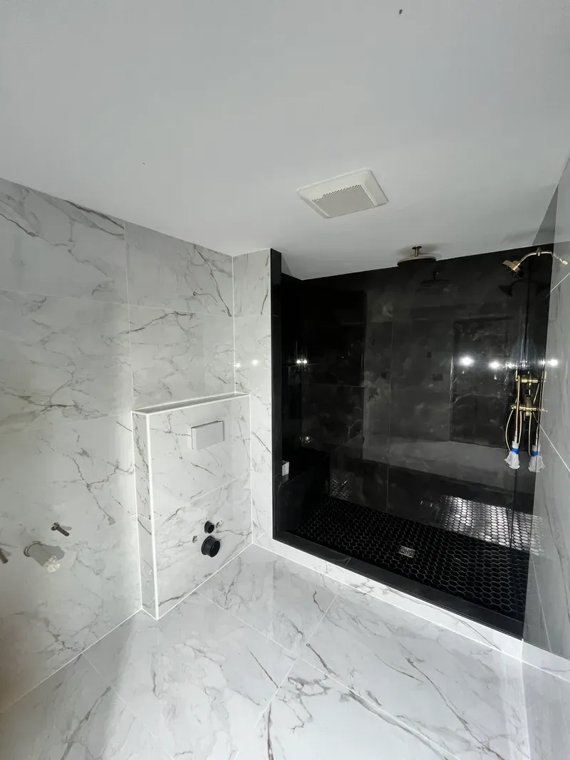 Finished shower tile — black large-format walls, hexagon mosaic floor