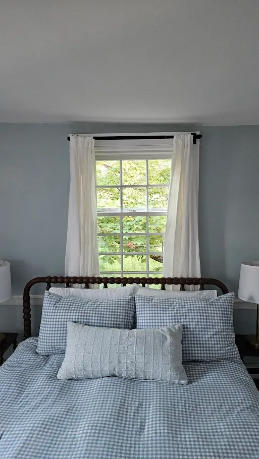 Replacement double-hung window with white interior trim and divided-light grilles in a Portsmouth, Rhode Island bedroom by Toensing Construction