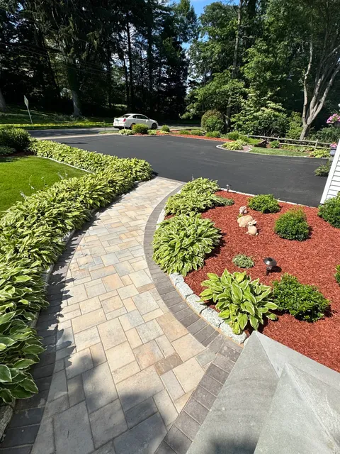 A beautifully curved custom stone walkway bordered by professional landscaping and mulch in Watertown.