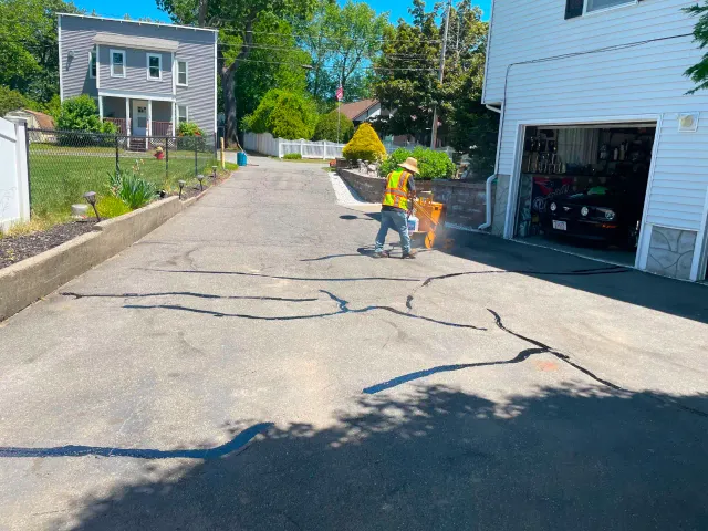 Rubberized crack filling on an asphalt driveway in Massachusetts