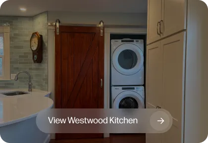 Kitchen with curved white island, tile backsplash, wooden barn door, stacked washer/dryer.