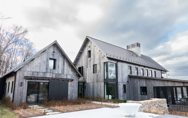 A large wooden house with a metal roof and a swimming pool in front of it.