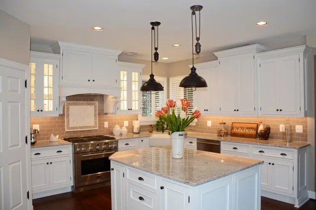 White kitchen with granite counters and custom hood surround