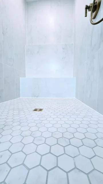 White-tiled custom walk-in shower in Glastonbury, CT bathroom remodel with hexagonal floor tiles and a small drain.
