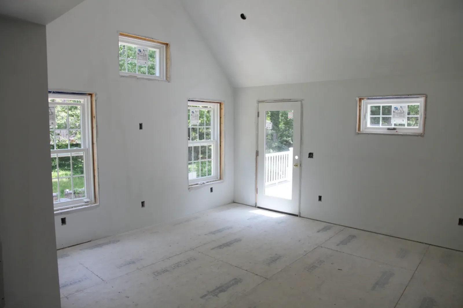 Vaulted great room during construction, with new windows and a door opening to the yard