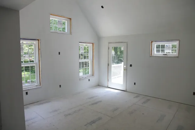 Vaulted great room during construction, with new windows and a door opening to the yard