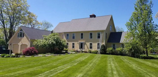 The outside of a large yellow home with a big lawn.
