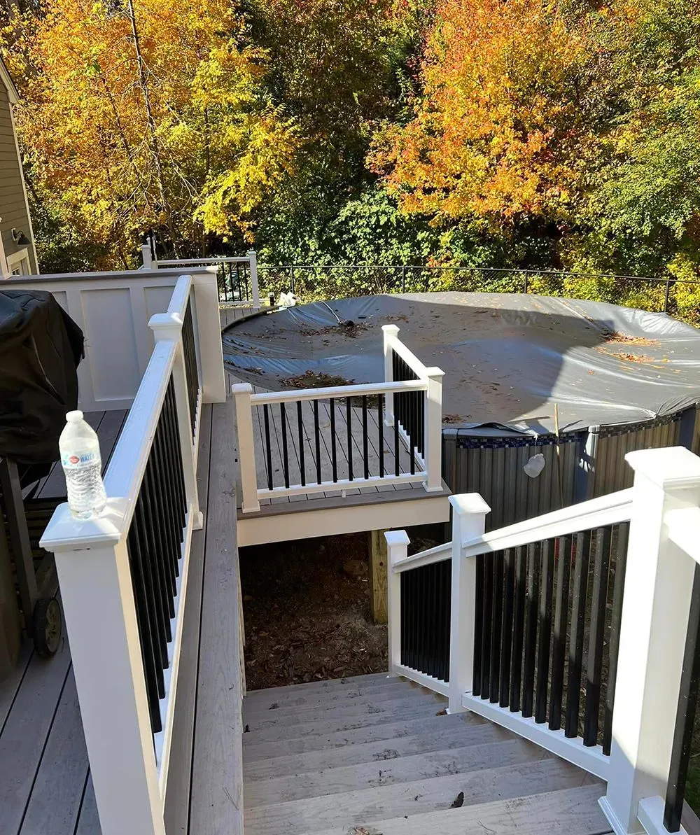 A deck with stairs leading up to a hot tub surrounded by trees