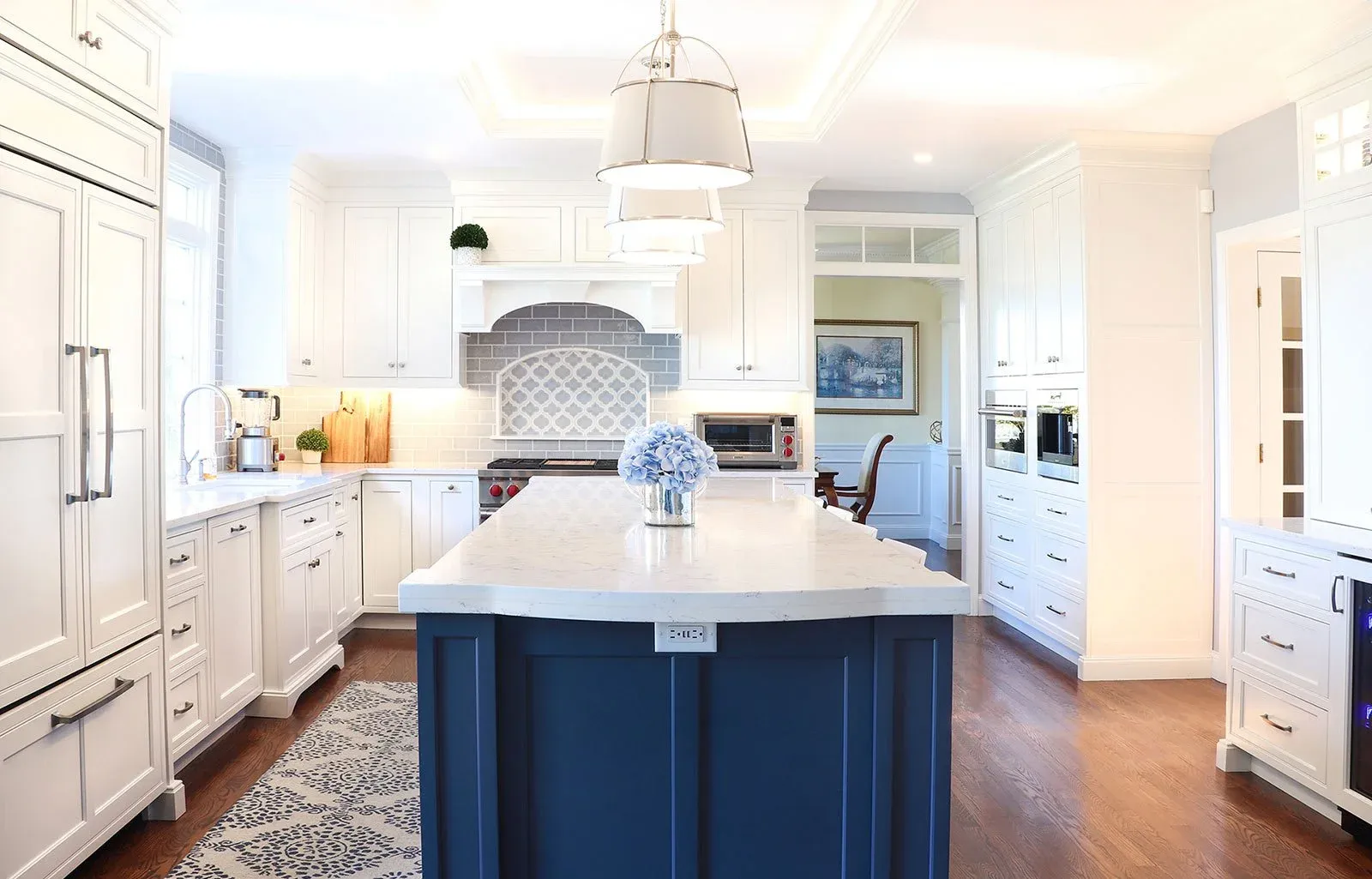 Coastal kitchen with vaulted ceiling and blue island with extra thick quartz countertop.