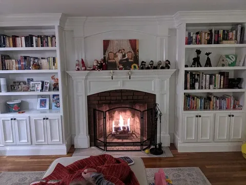 Fireplace with a burning fire and white built-in bookshelves