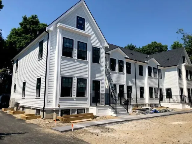 New white townhouse row under construction with steps, porches, and dirt foreground