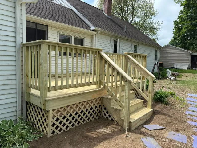 A wooden deck with stairs is in front of a house.