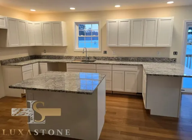 Kitchen with white cabinets, granite countertops, and an island, with wood floors.
