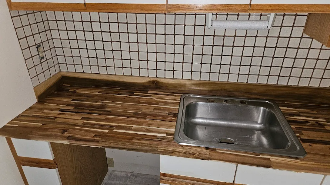 Custom wood butcher block countertop with white mosaic tile backsplash and stainless steel sink by Toensing Construction in Rhode Island