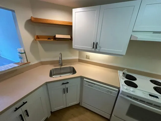 Small kitchen with white cabinets, stainless steel sink, and stove.