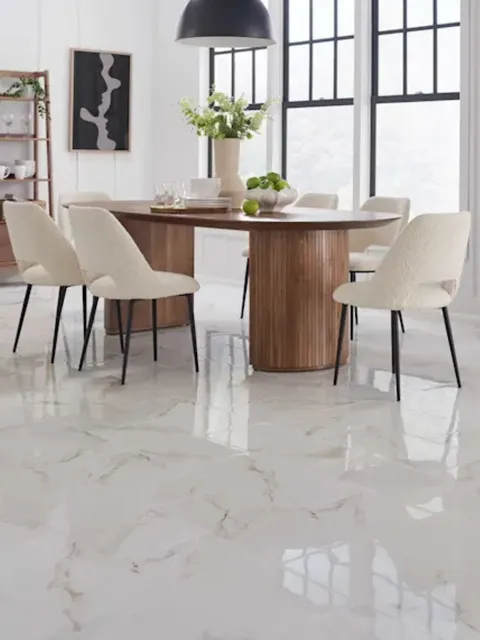 Modern dining room featuring a wooden pedestal table and white textured chairs on a polished, marble-look tile floor.