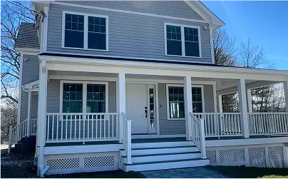 Two-story gray house with white trim, wide front porch, and steps leading up to the front door.