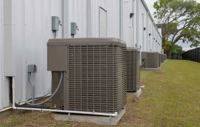A row of air conditioners are sitting outside of a building.
