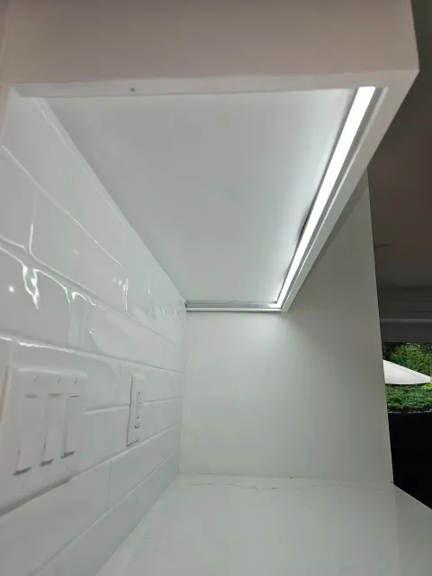 White kitchen shelf with under-cabinet lighting and tiled wall