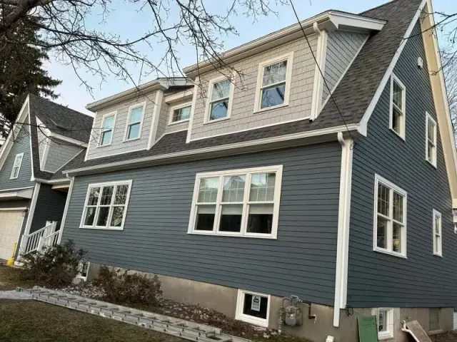 Custom home exterior in Wakefield, MA featuring blue clapboard siding, multiple windows, and a second-floor addition, showcasing modern residential architecture.
