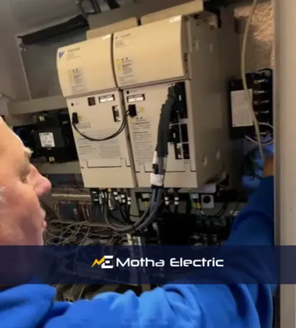 Electrician working on electrical panel installation with Motha Electric branding.