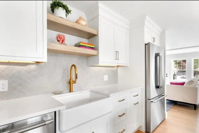 A kitchen with white cabinets, stainless steel appliances, a sink and a refrigerator.