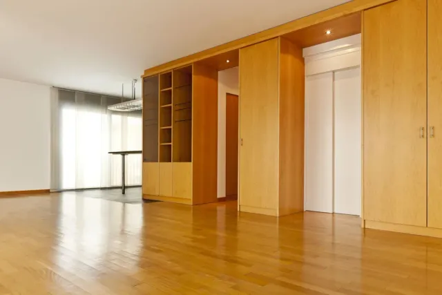 Empty, light-wood floored room with built-in cabinetry, shelving, and a white-doored elevator.