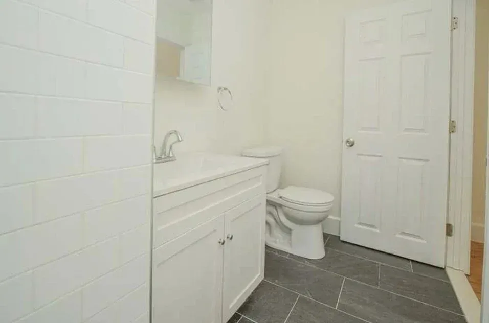 A bathroom with a sink, toilet, and tile floor.