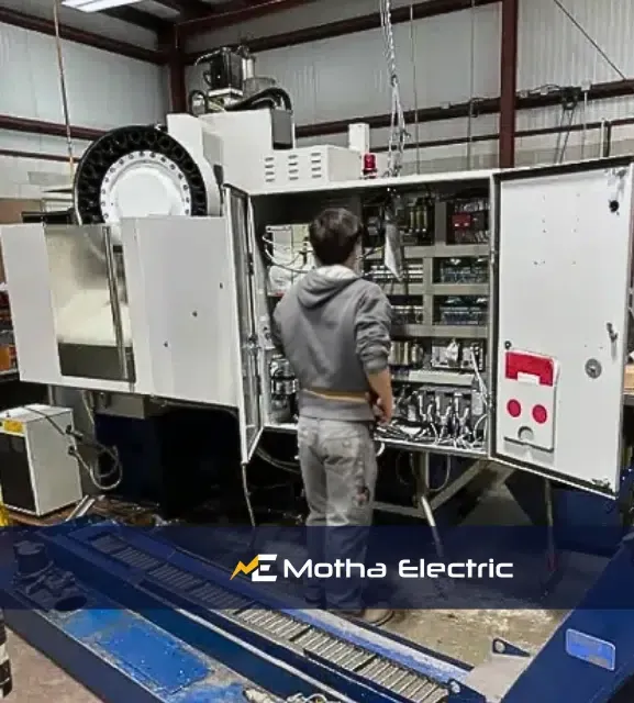 Electrician inspecting electrical panel with open doors, showcasing wiring and components, Motha Electric branding visible, emphasizing expertise in electrical safety and installations.