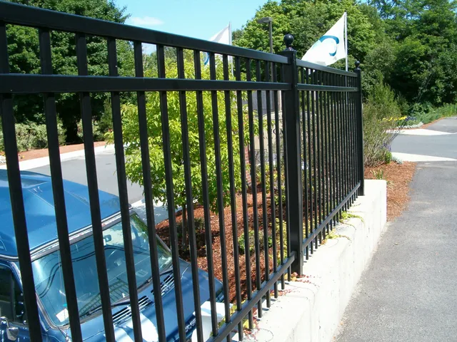 Black ornamental fence along a roadside wall
