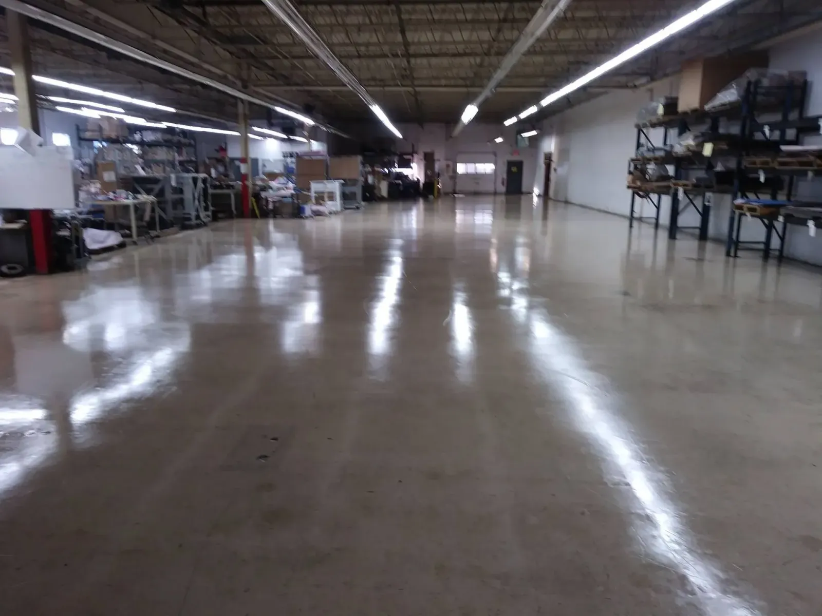 A large warehouse with a shiny floor and lots of shelves.