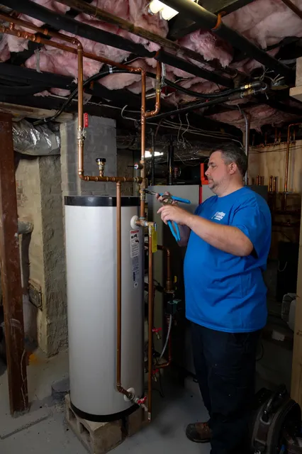 Phillips Plumbing technician working on a water heater in a basement