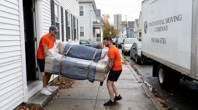 Movers carrying wrapped couch from apartment during small move