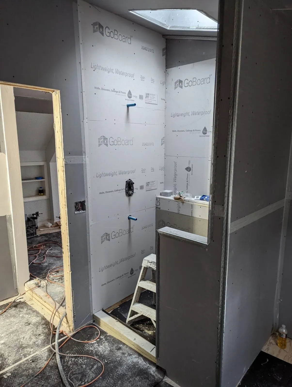 A bathroom under construction with a ladder in the corner.