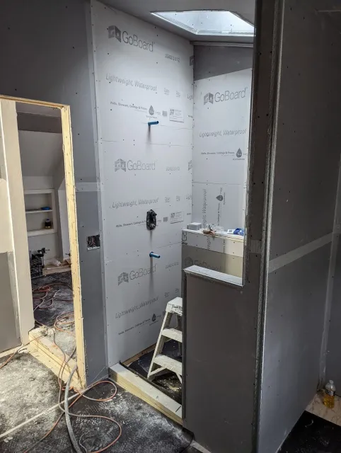 A bathroom under construction with a ladder in the corner.