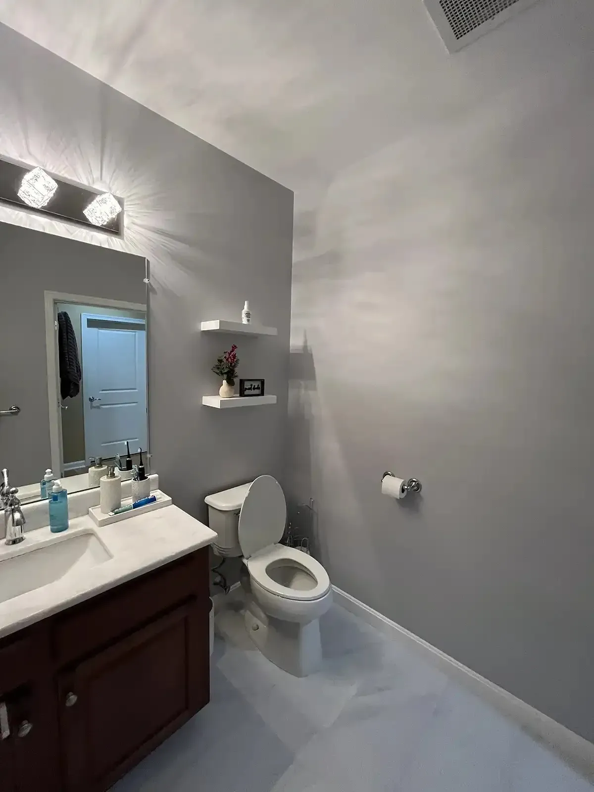 Renovated bathroom with floating shelves and vanity lighting