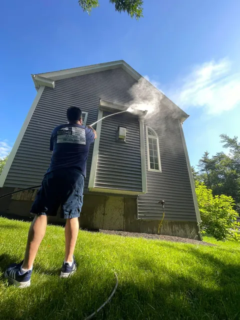 Worker Pressure Washing House