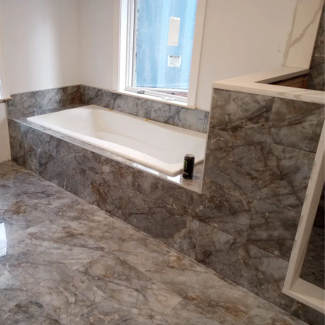 Drop-in bathtub surround with gray marble-look porcelain tile by Link Services Pro in Millbury, MA