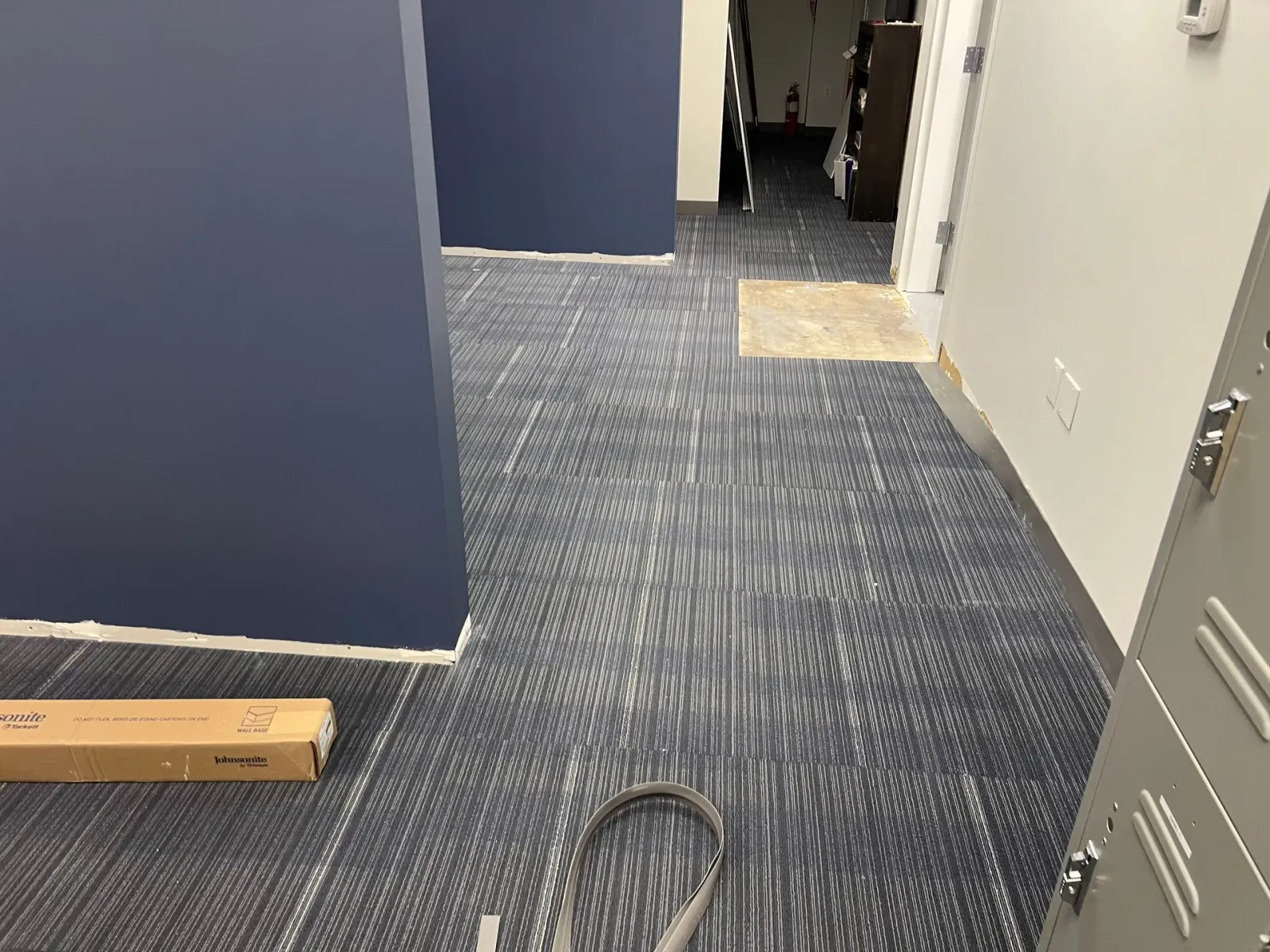 A room with a carpeted floor and a vacuum cleaner on the floor.