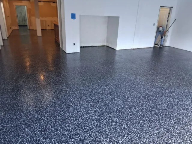 A dark flake floor across a wide room with white walls and an open door