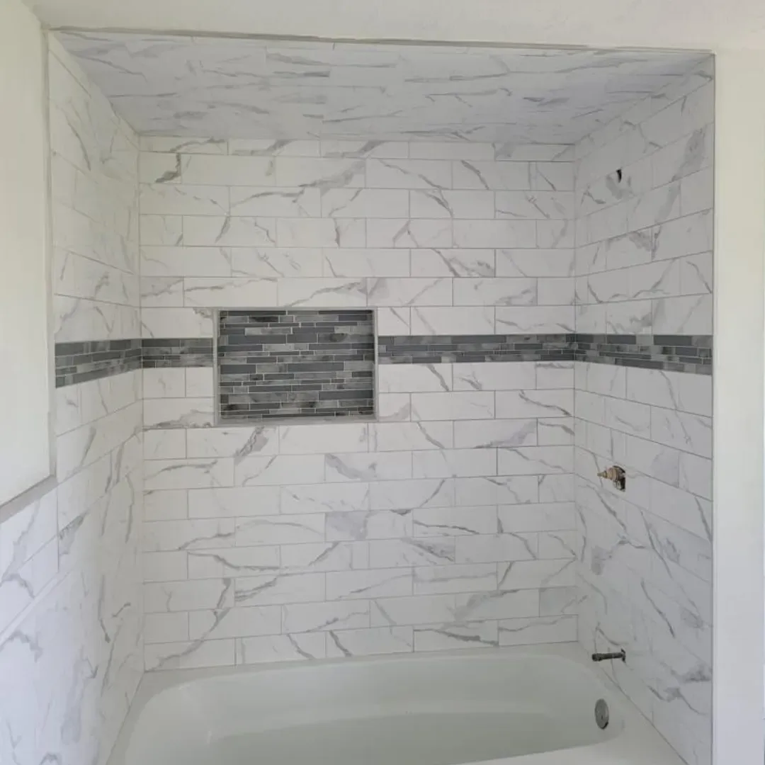 Marble subway tile shower wall with glass mosaic feature stripe by Link Services Pro in Millbury, MA