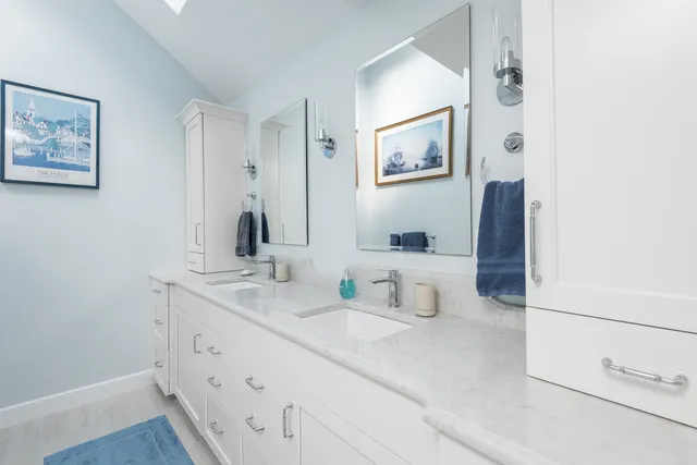 Hingham coastal primary bath with white Tedd Wood double vanity, skylight, and harbor art