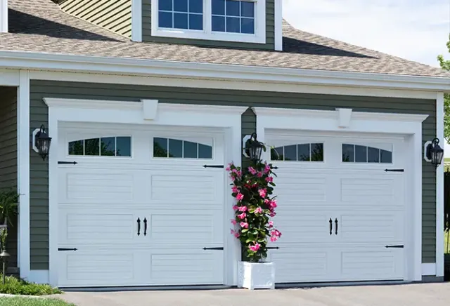 Elegant white residential garage door in Vantage Shaker style with Richmond Arch Long Inserts on a green home in Lincoln, RI. Sold by Quality Overhead Doors, built by Garaga