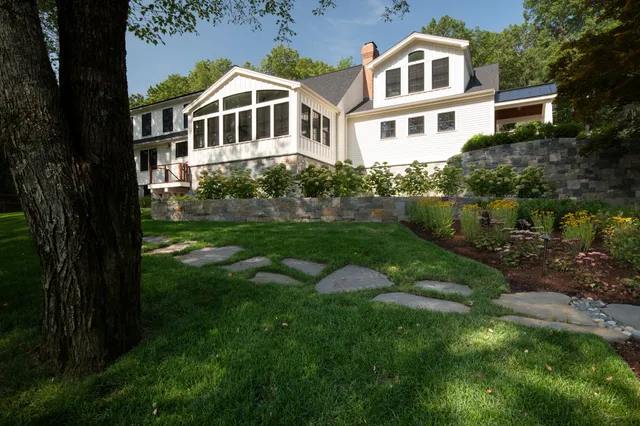 A beautiful highlight from a recent project. We love how these natural stepping stones gently lead you through the lawn, connecting the different spaces of the garden. The stone retaining walls add structure and create beautiful planting areas while helping this sloped site feel more intentional and connected to the main house. A low hedge of FlowerFull Smooth Hydrangeas softens the wall and creates a cozy transition from the front yard to the home. A great example of how thoughtful hardscape can be both practical and beautiful!

@jhs_landscape_const 
@dpturf.irrigation 
@thomasbuckboroughassociates 

#LandscapeArchitect #HardscapeDesign #GardenDesign #LandscapeInspiration #AngieVergeLandscapeDesign