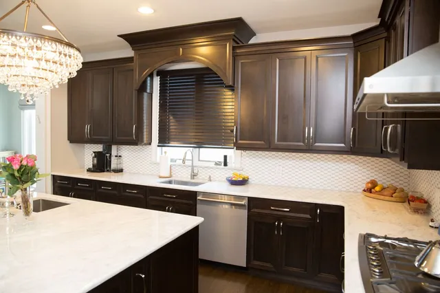 Dark maple kitchen with quartz counters and arched hood surround